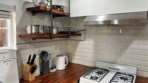 Una cucina con fornelli, pentole, una macchina da caffè e utensili sul piano di lavoro.