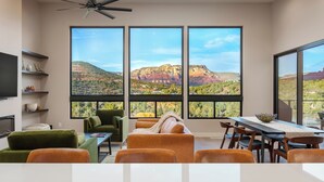 A modern living room with a large window overlooking a mountainous landscape. - Red Sky on Caballo Dr. - Great Views & Central (Sedona)