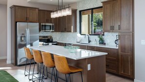 A modern kitchen with wooden cabinets, stainless steel appliances, and a central island with bar stools. - Red Sky on Caballo Dr. - Great Views & Central (Sedona)