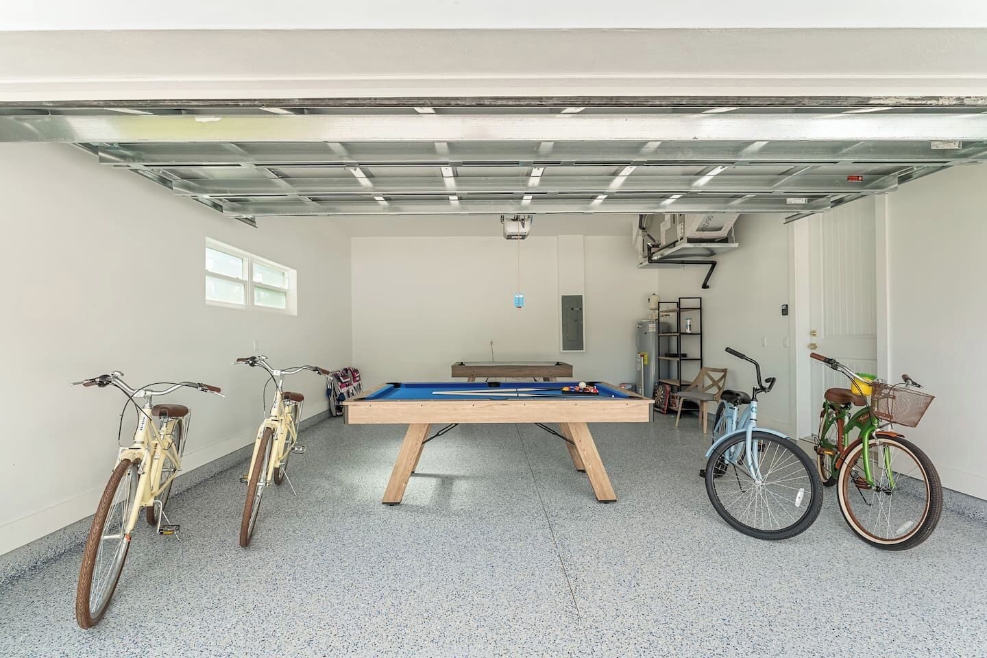 A garage with a pool table, bicycles, and a ping pong table.