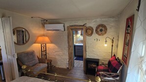 A cozy room with a fireplace, a sofa, a chair, a lamp, and a mirror. - Cozy 2-bedroom cabin on a working mini farm in San Fidel with AC on old route 66 (San Fidel)