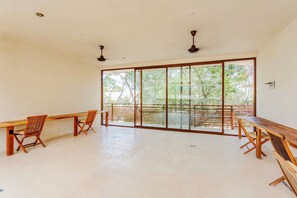 A spacious room with large sliding glass doors, wooden furniture, and ceiling fans. - Luxury Jungle Condo in Tulum with Pools, Private Cenotes & Gated Community (Tulum)