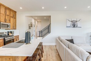A modern kitchen with wooden cabinets, a large island, and a dining area.