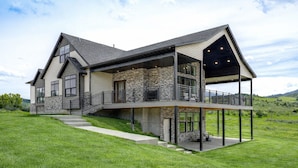 A modern two-story house with a stone facade, large windows, and a covered outdoor area.