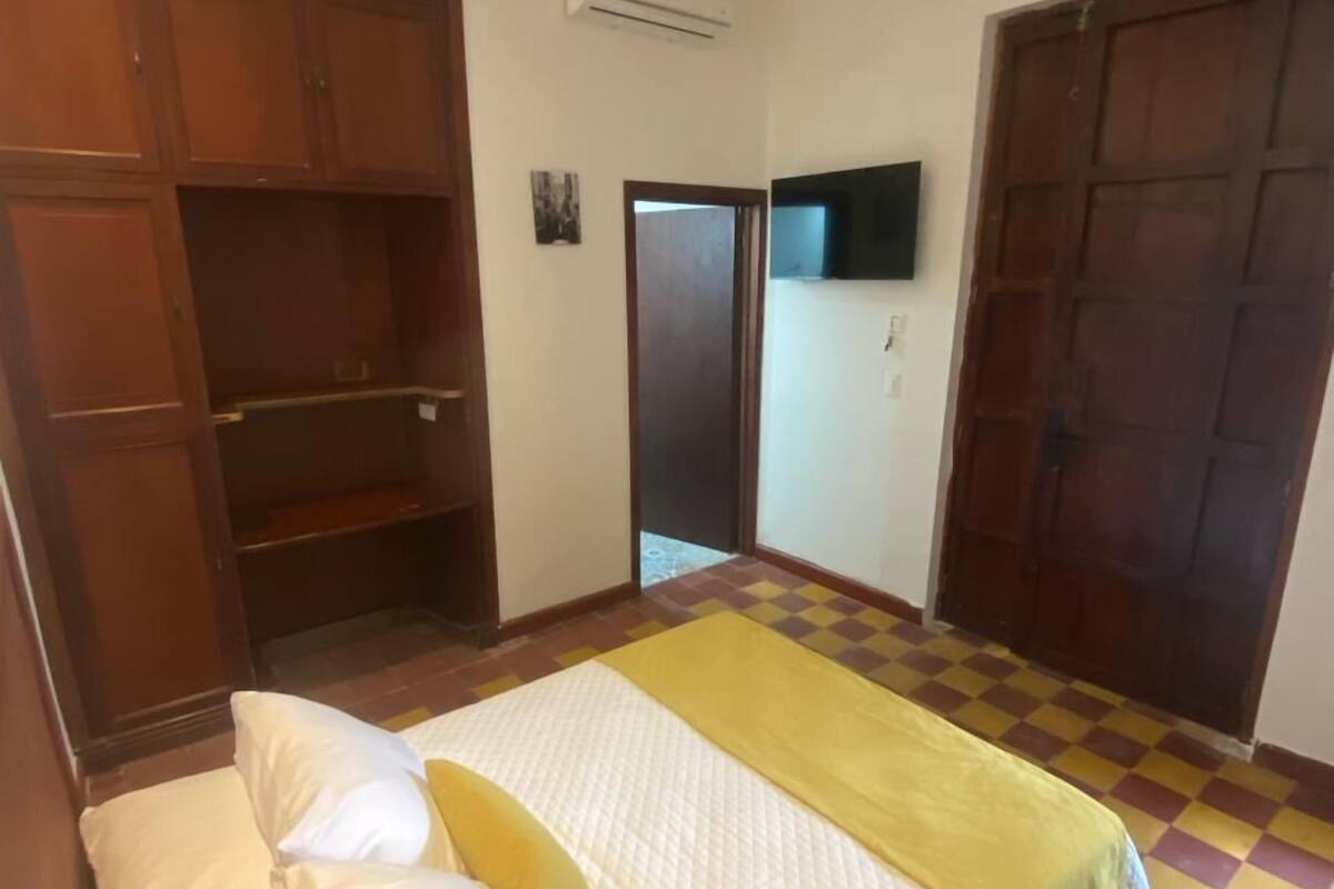 Une chambre à coucher avec un lit, une armoire, une télévision et un sol à carreaux.