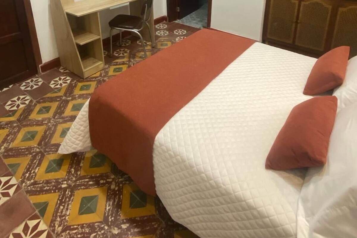Une chambre à coucher comprenant un lit, un bureau, une chaise, une armoire et un téléviseur.