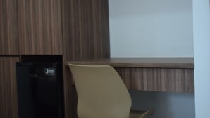 A room with a wooden panel wall, a black refrigerator, and a beige chair. - Hotel Boutique Iyarí (Palmira)