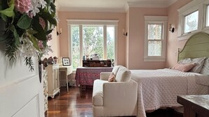 Un dormitorio con cama, silla, escritorio y ventana.