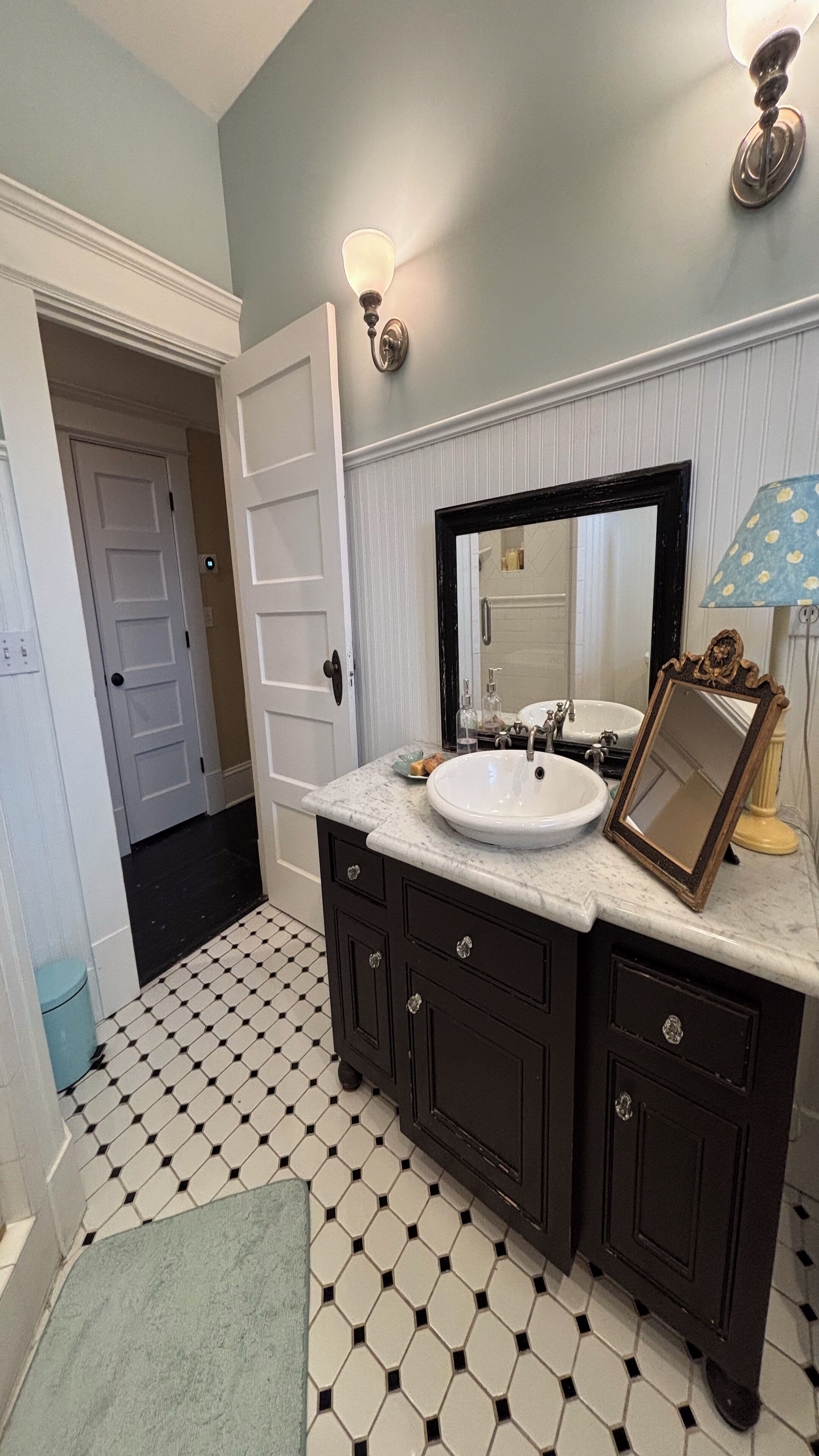 A bathroom with a white sink, dark wooden cabinets, a large mirror, and a tiled floor.