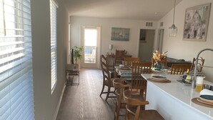 A spacious kitchen with a long countertop, wooden chairs, and a dining table. - Breeze Retreat (St. Augustine)