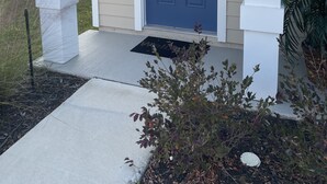 A front door with a wreath, a welcome mat, and a potted plant. - Breeze Retreat (St. Augustine)