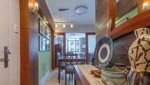 A hallway with wooden walls, a dining area with a table and chairs, and a decorative vase on a table.