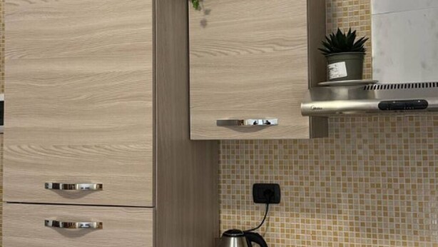 Una cucina con mobili in legno, una cappa in acciaio inossidabile e uno schienale piastrellato.