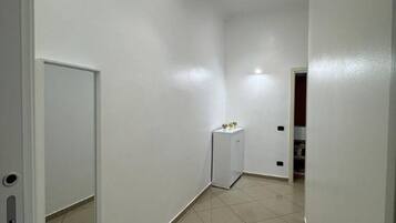 A narrow hallway with white walls and tiled flooring.