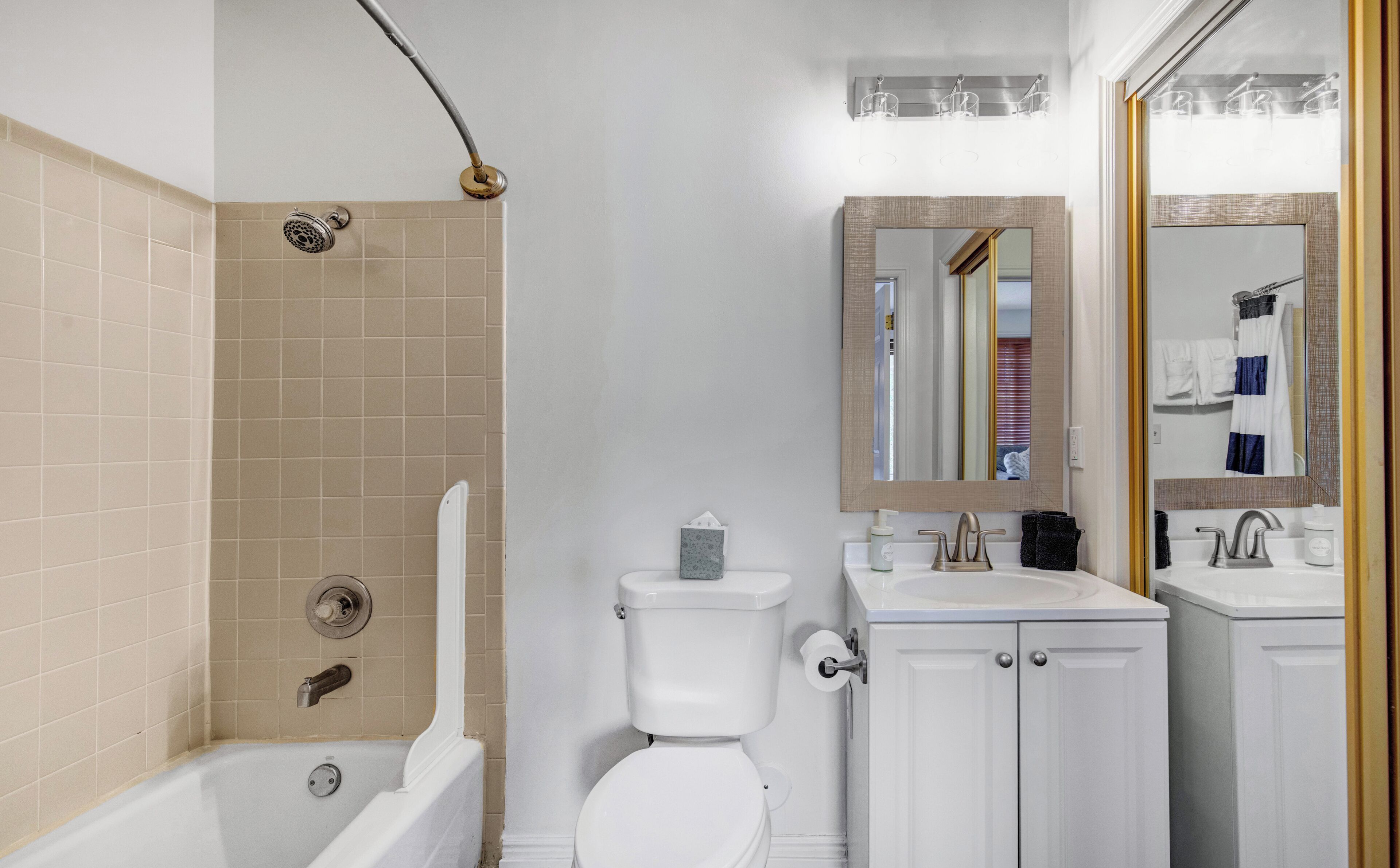 A bathroom with a bathtub, toilet, sink, and mirror.