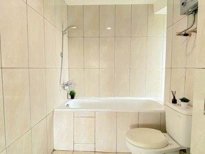 Ein Badezimmer mit Badewanne, Toilette und einem kleinen Topfpflanzen.