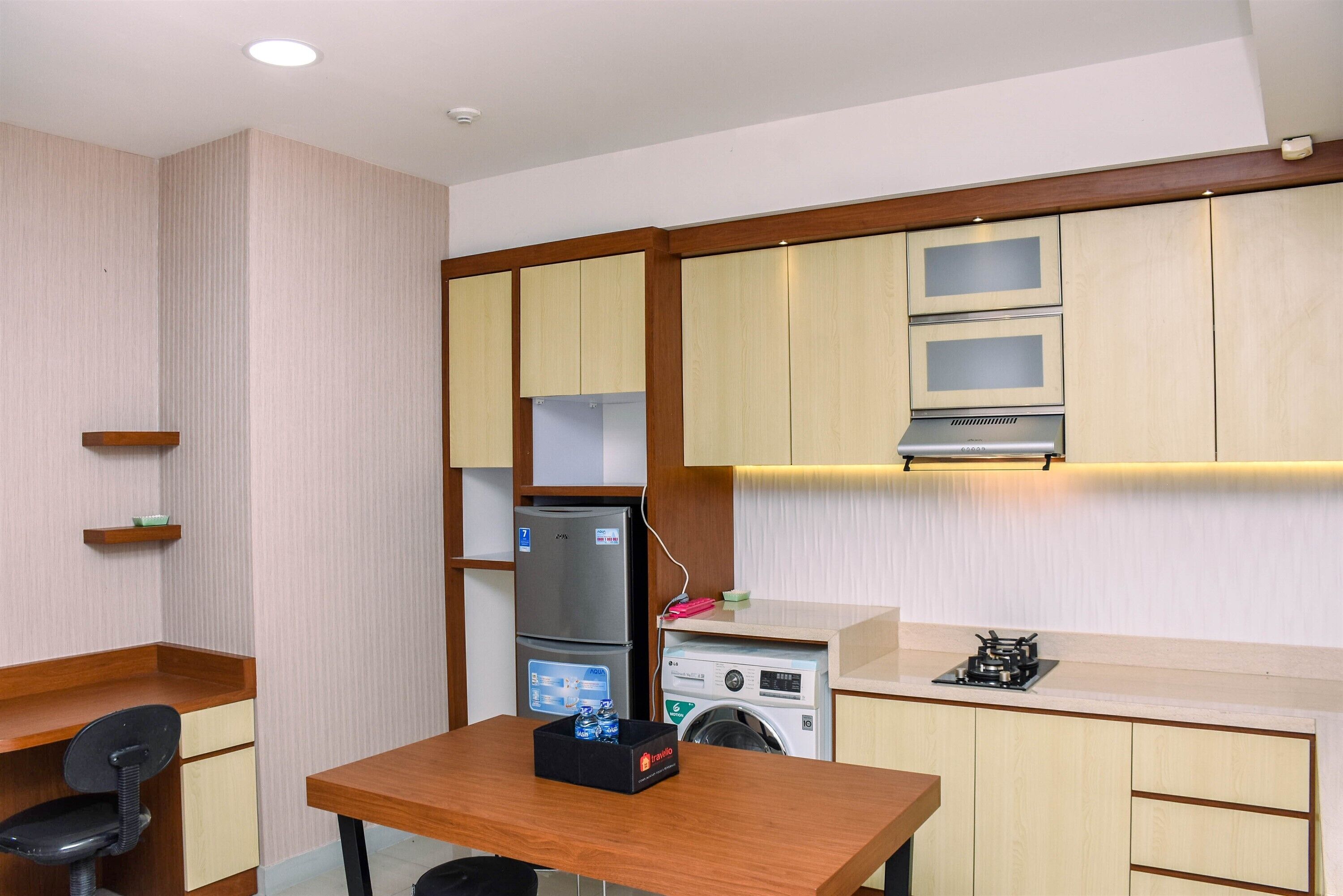 A compact kitchen with a refrigerator, washing machine, and a small table with a box.