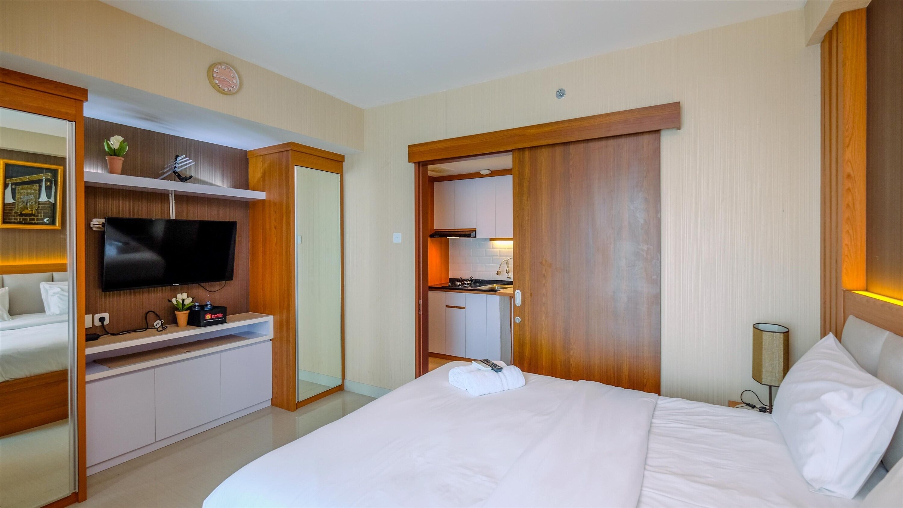 A hotel room with a bed, a TV, a kitchenette, and a bathroom.
