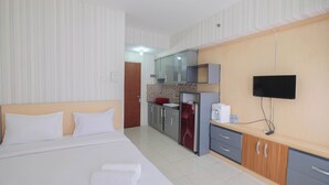 A hotel room with a bed, a TV, a kitchenette, and a bathroom. - Cozy Stay Studio Room At Taman Melati Margonda Apartment (Depok)