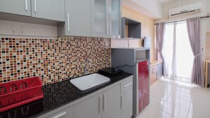 A kitchen with a tiled backsplash, a sink, cabinets, and a refrigerator. - Cozy Stay Studio Room At Taman Melati Margonda Apartment (Depok)