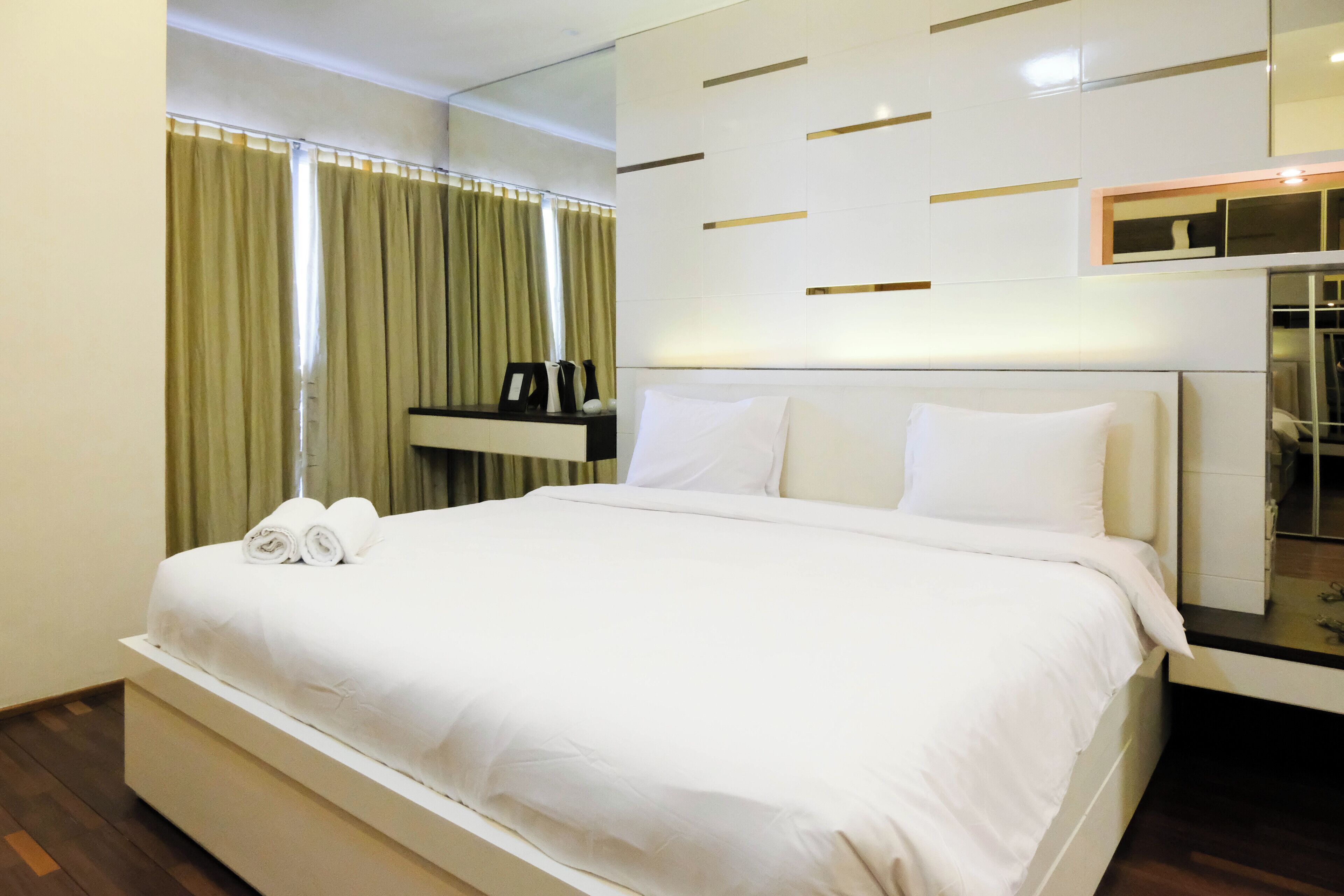 Ein modernes Hotelzimmer mit einem großen Bett, einem Nachttisch und einem Spiegel.