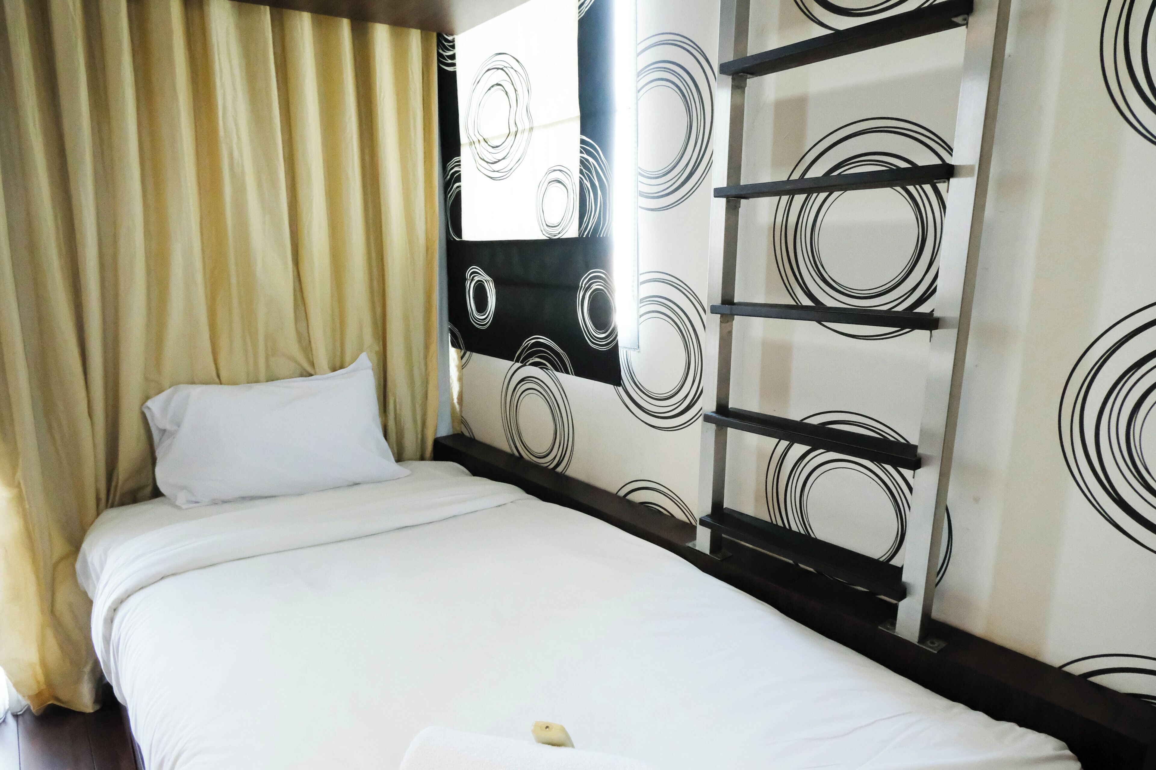 Ein Hotelzimmer mit einem Bett, Vorhängen und einer Wand mit kreisförmigen Mustern.