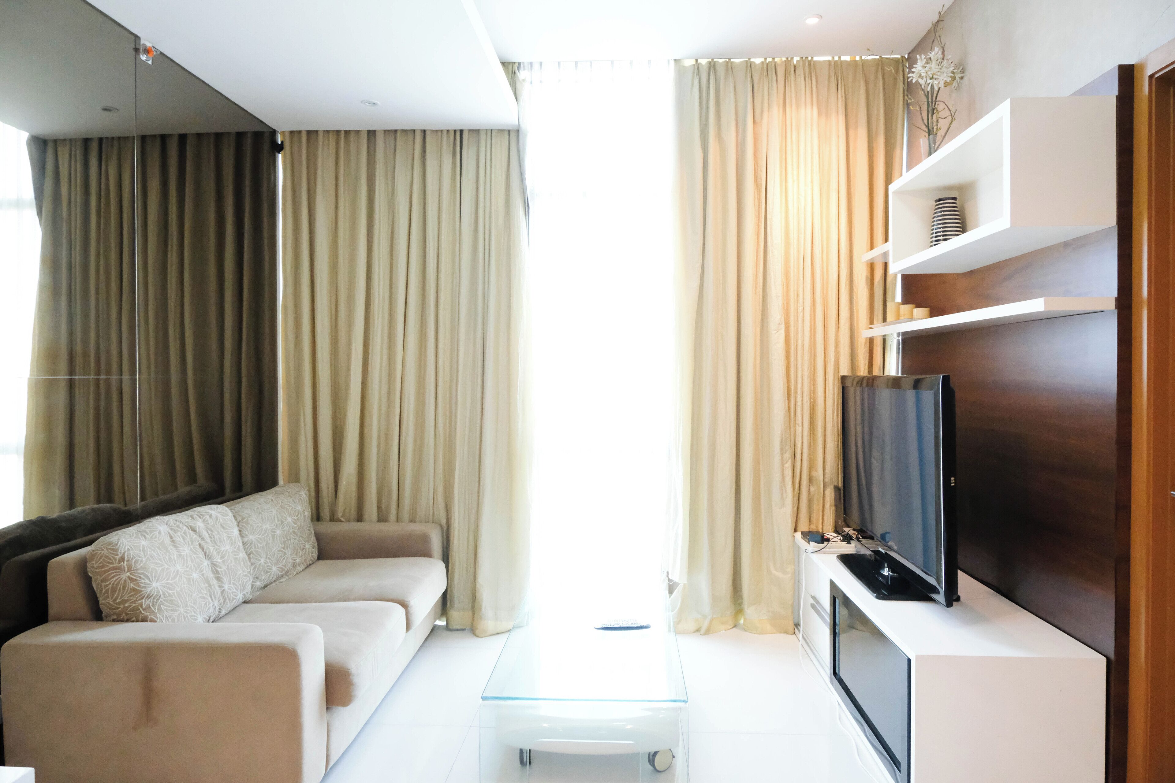 Una sala de estar moderna con sofá, mesa de centro de vidrio, televisor de pantalla plana y estanterías empotradas.