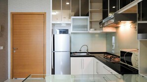 A modern kitchen with a refrigerator, stove, and cabinets. - Spacey 2Br With Access Mall At Apartment Aryaduta Residence Surabaya (Surabaya)