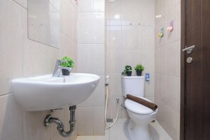 A bathroom with a white sink, toilet, and shower. There are potted plants on the toilet and a towel on the toilet seat. - Best Deal And Elegant Studio Citra Living Apartment (Jakarta)