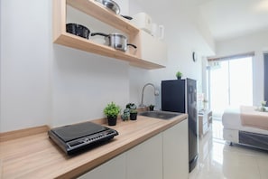 Eine moderne Küche mit Holzarbeitsplatten, einem eingebauten Backofen, einer Spüle und einem Kühlschrank. Auf der Arbeitsfläche stehen Topfpflanzen und ein Fenster lässt natürliches Licht herein.