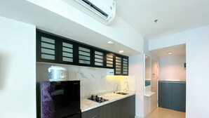 A modern kitchen with a built-in stove, a sink, and a microwave. - Well Furnished And Cozy Stay Studio Grand Kamala Lagoon Apartment (Bekasi)