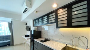 A modern kitchen with dark cabinets, a marble countertop, and a stainless steel sink. - Well Furnished And Cozy Stay Studio Grand Kamala Lagoon Apartment (Bekasi)