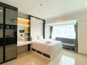 Una habitación de hotel moderna con una cama grande, un escritorio empotrado, un tocador con espejo y una ventana con cortinas.