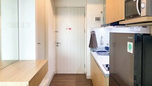 A compact kitchen with a microwave, refrigerator, and sink. - Good Deal And Homey Studio Grand Kamala Lagoon Apartment (Bekasi)