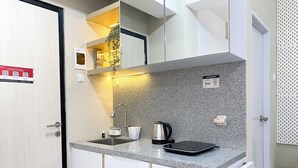 A compact kitchenette with a granite countertop, a kettle, a coffee maker, and a small sink. - Minimalist And Homey Studio At Grand Kamala Lagoon Apartment (Bekasi)