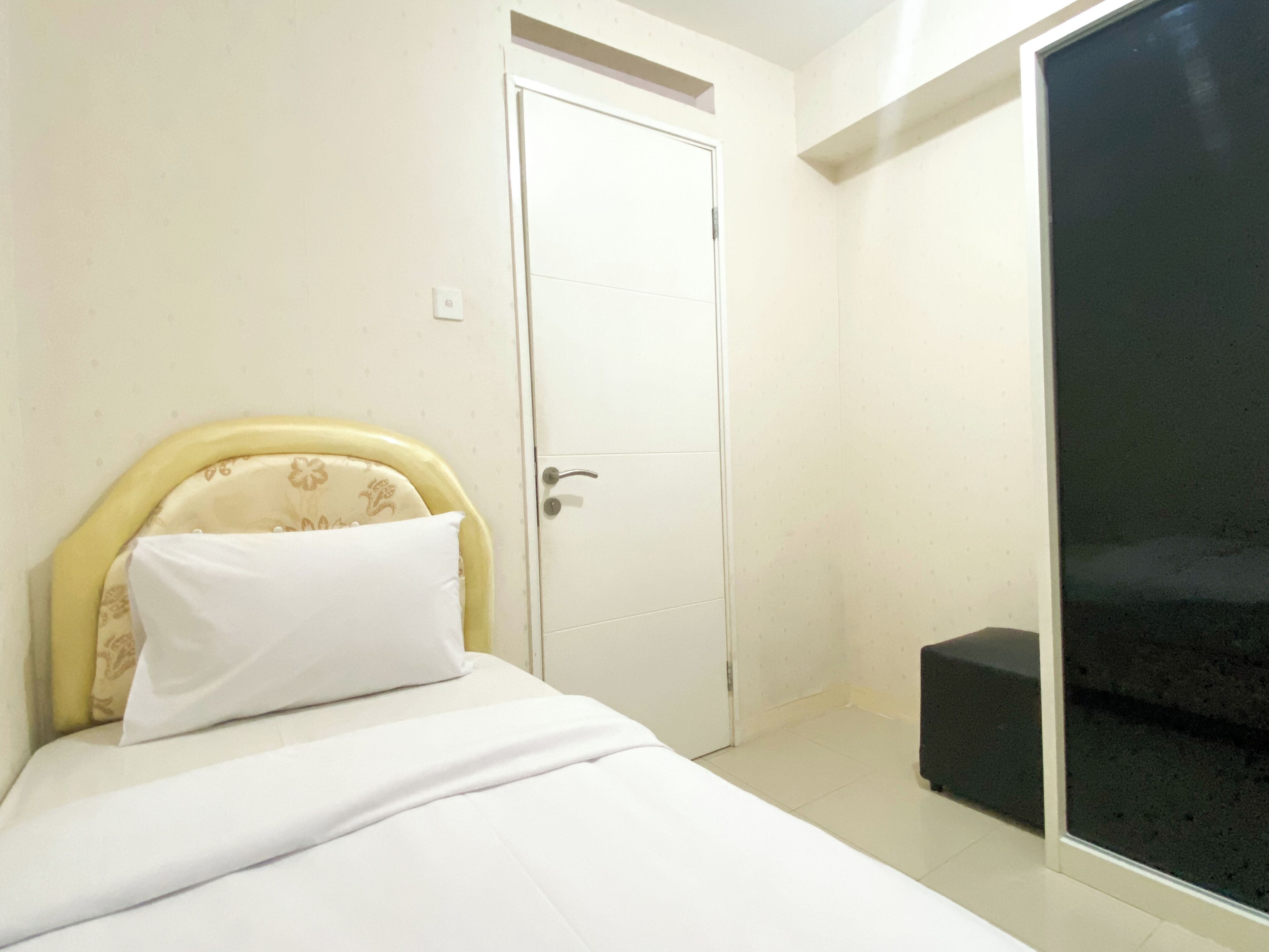 A bedroom with a bed, a white door, and a black bench.