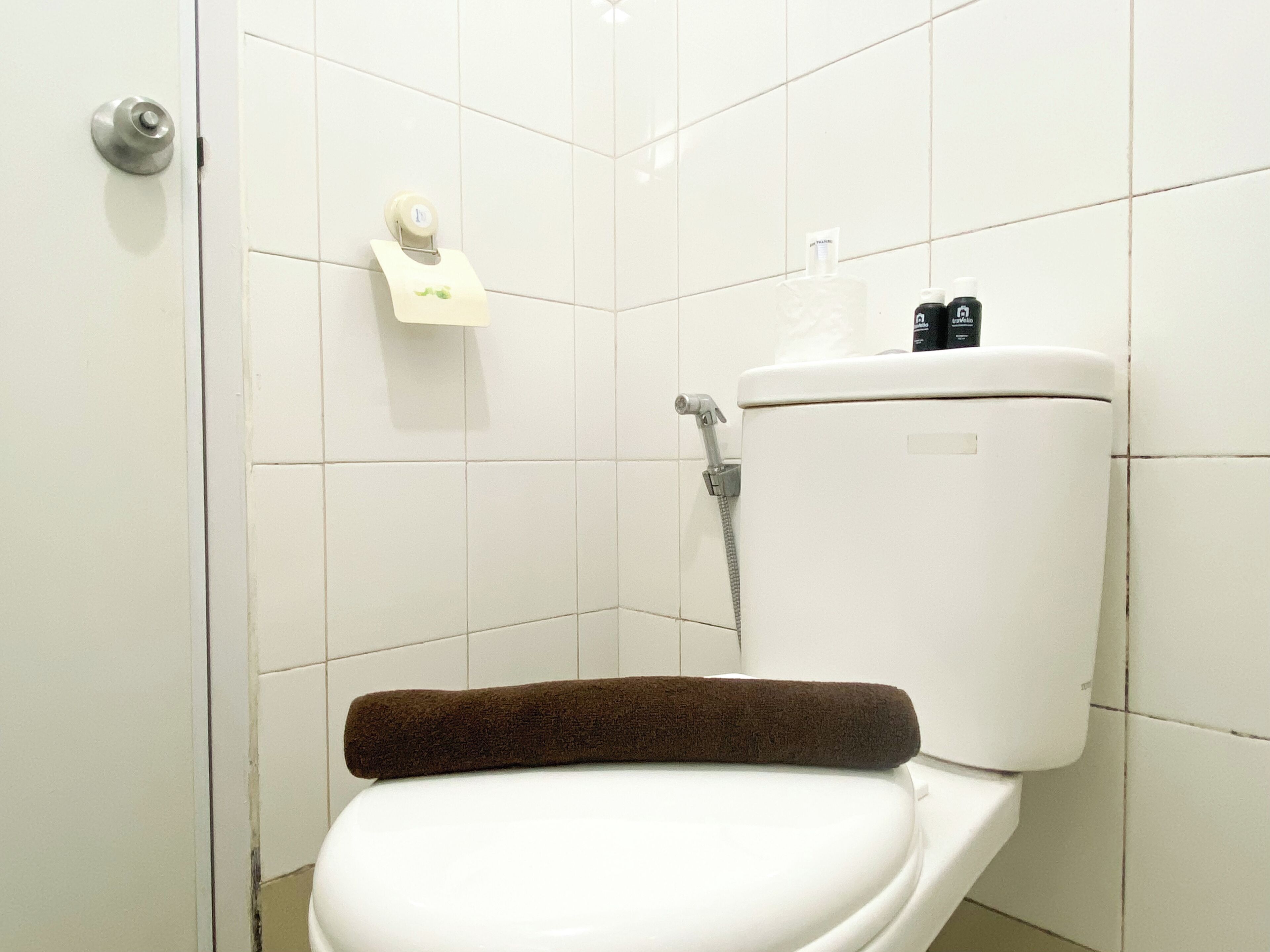 A bathroom with a white toilet, a towel, and a toilet paper holder.
