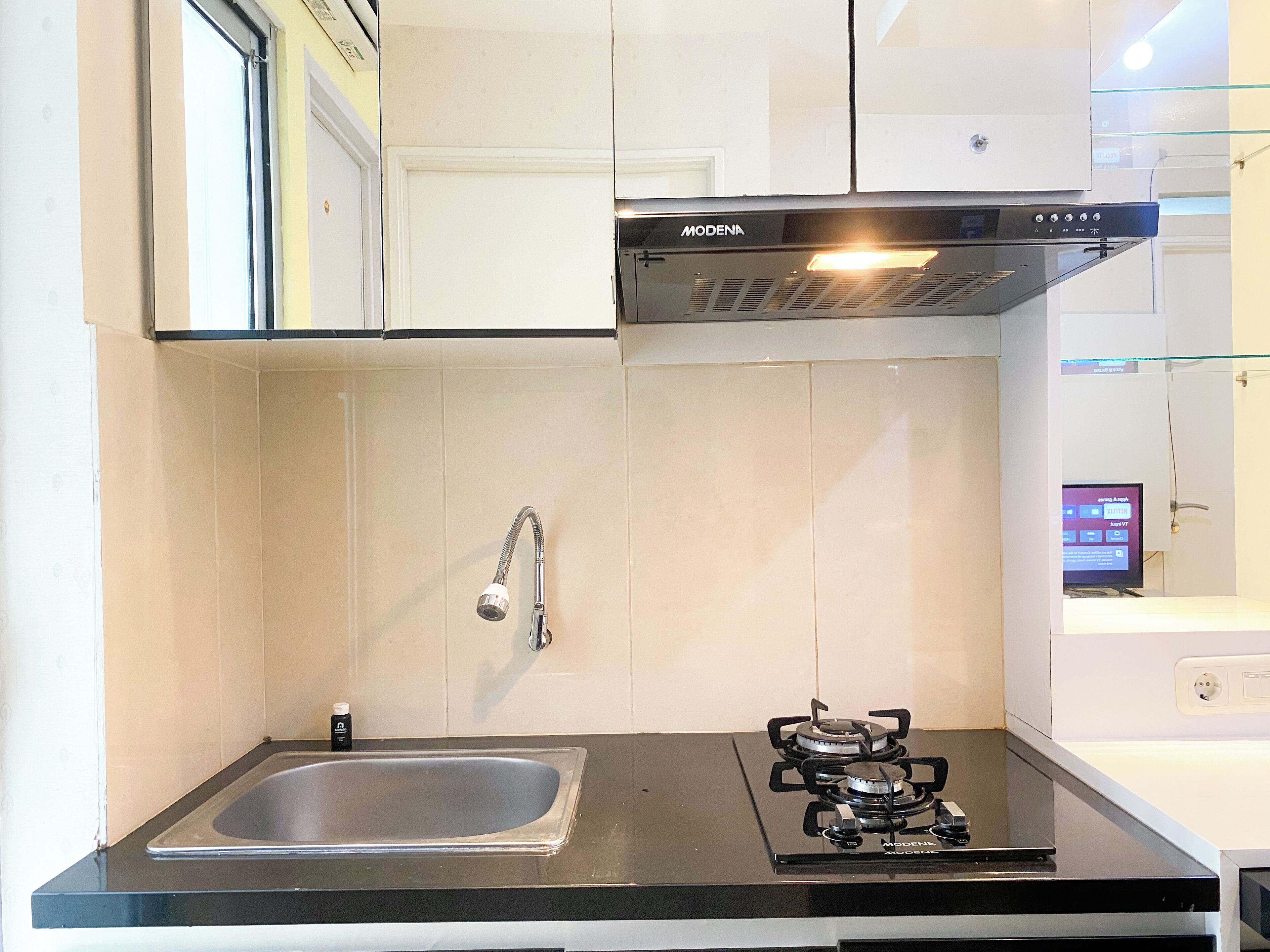 A kitchen with white cabinets, a stainless steel sink, a gas stove, and a modern range hood.