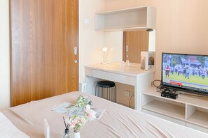 Ett hotellrum med en säng, ett skrivbord, en tv och en spegel.