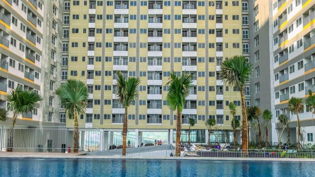 A modern apartment building with a swimming pool in the foreground. - Good And Spacious Studio Lrt City Royal Sentul Park Apartment (Bogor)