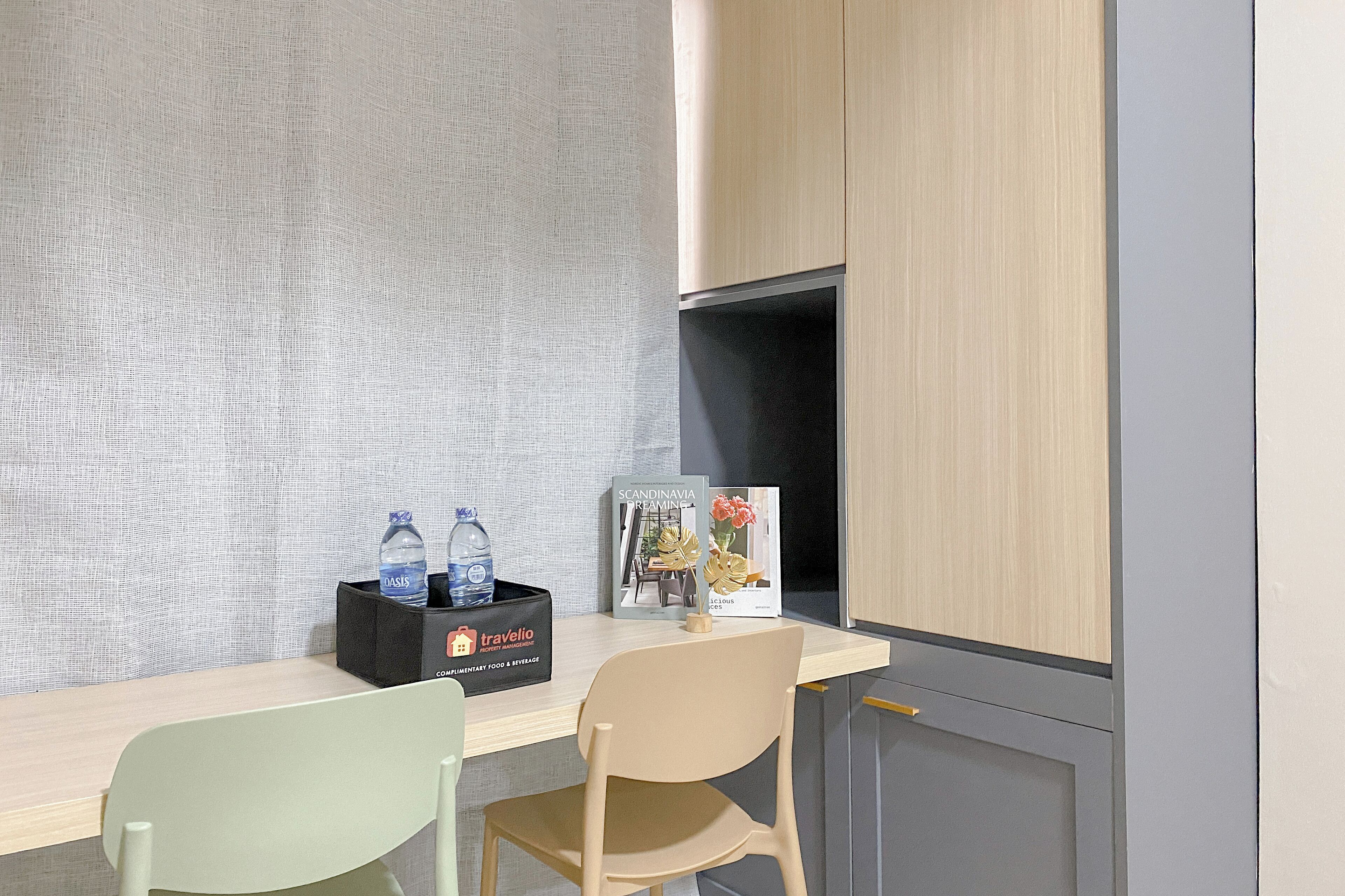 A room with a light-colored desk, a black box with water bottles, a book titled 'Scandinavian Kitchens', and a chair.