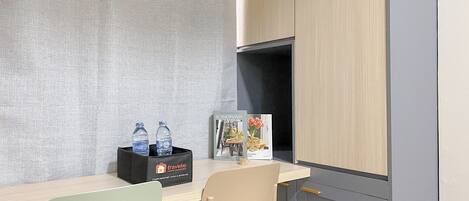 A room with a light-colored desk, a black box with water bottles, a book titled 'Scandinavian Kitchens', and a chair.