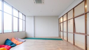 A room with large windows, a wooden floor, and colorful cushions. - Good And Spacious Studio Lrt City Royal Sentul Park Apartment (Bogor)
