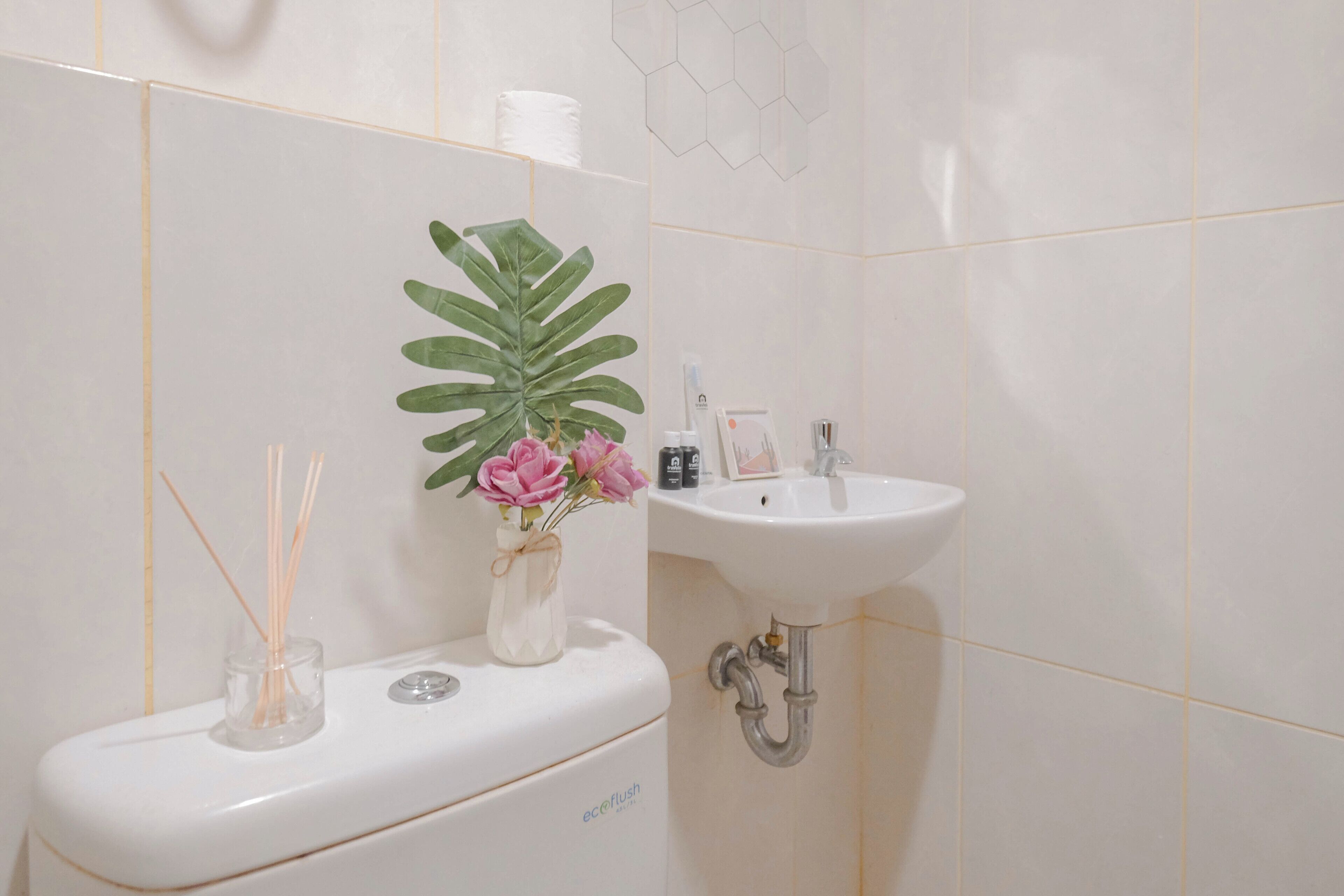A bathroom with a toilet, sink, and a plant with flowers.