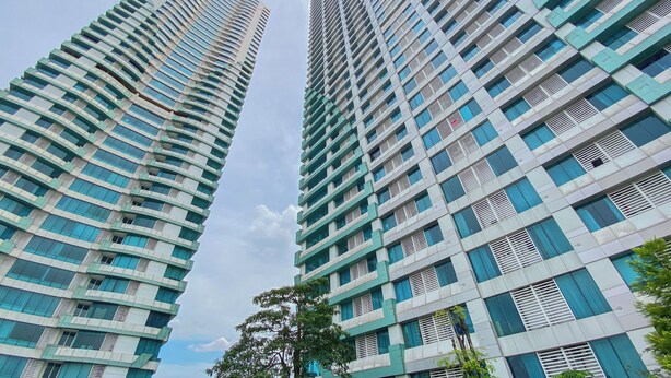 Dos edificios altos con un diseño arquitectónico moderno, que presenta una estructura de ventanas y balcones.