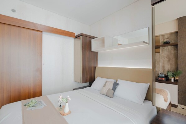 Une chambre d’hôtel moderne, équipée d’un lit, d’une table de chevet et d’un miroir.