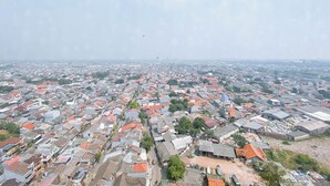 An aerial view of a densely populated urban area with numerous buildings and streets. - Compact Wood Accents Studio Apartment Grand Kamala Lagoon (Bekasi)