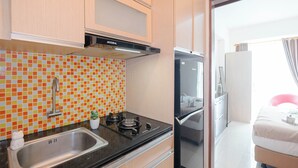 Une cuisine de taille réduite équipée d’une cuisinière à gaz, d’un évier et d’un réfrigérateur.