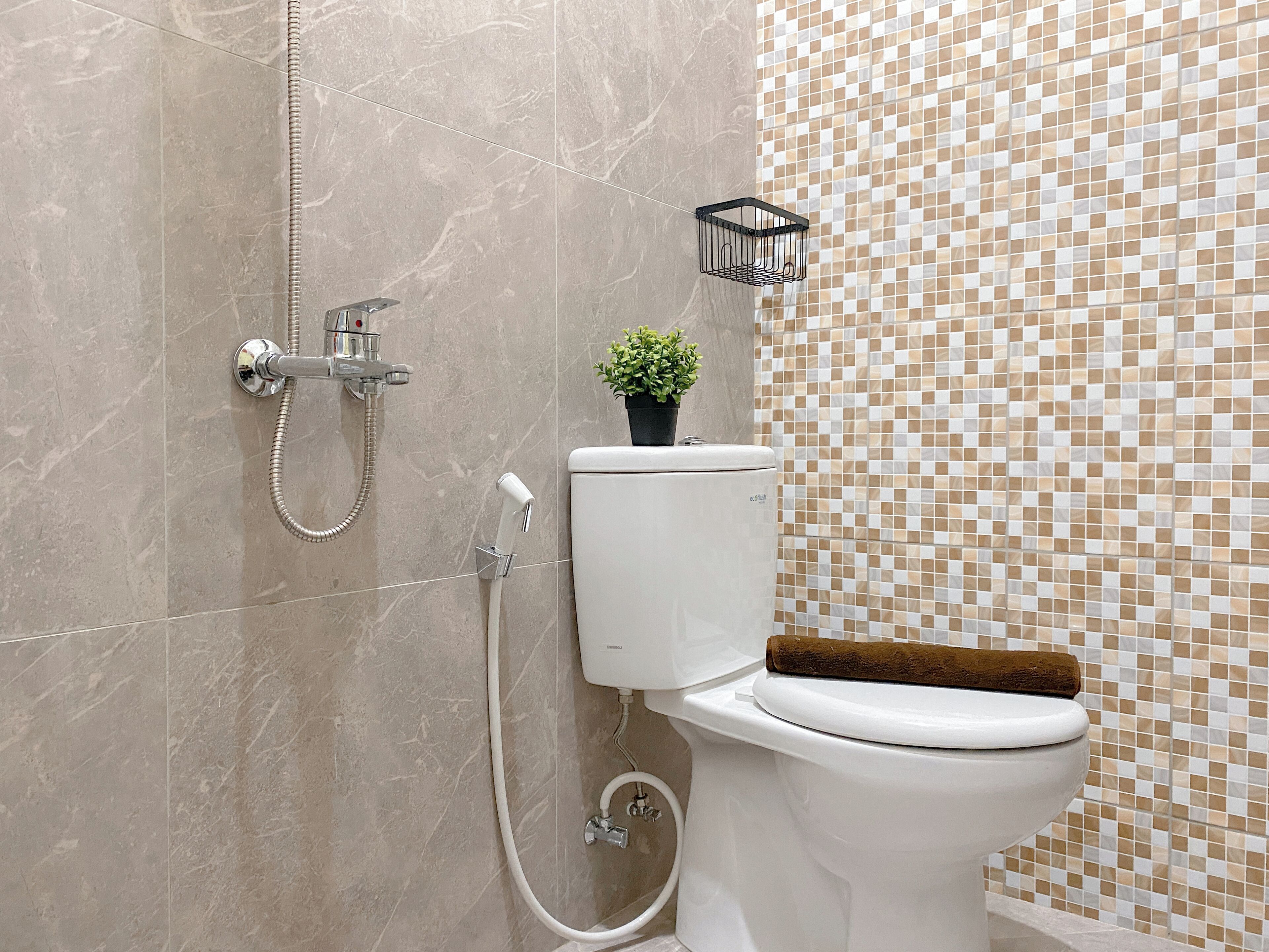 Un baño con inodoro, ducha y pared de azulejos decorativos.