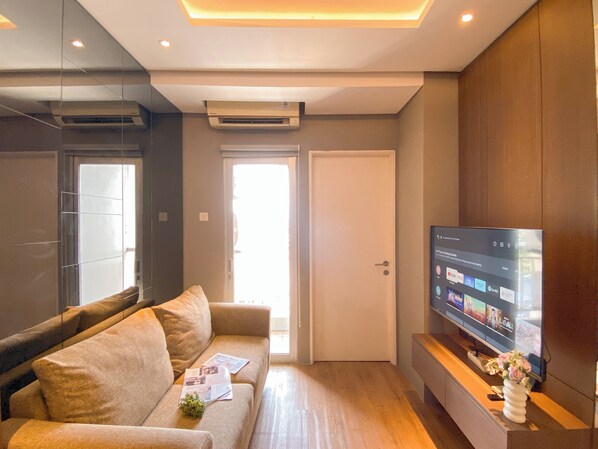 Een moderne woonkamer met een bank, een flatscreen televisie en een houten kast.